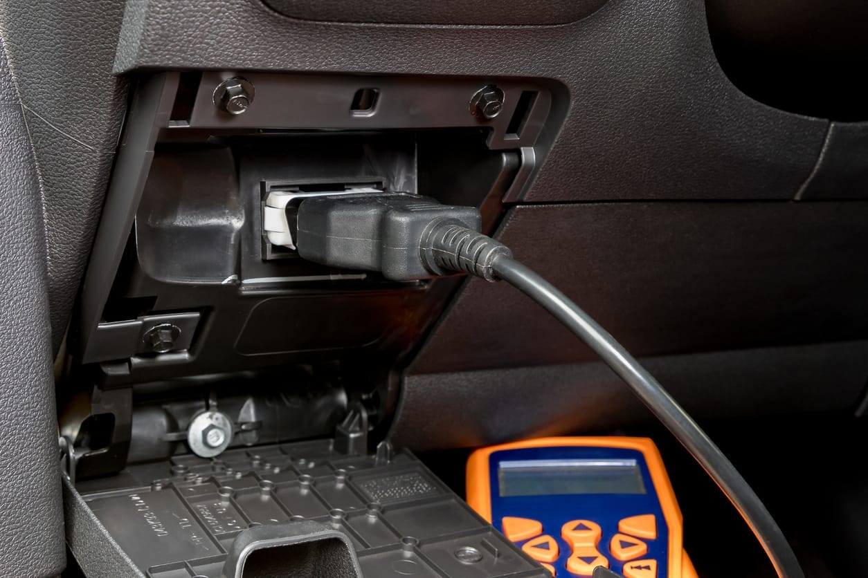 Diagnoseverktøy koblet til bilens OBD-kontakt under dashbordet