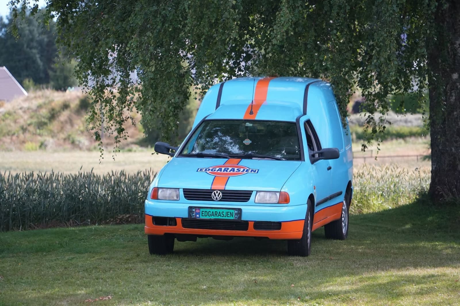 Den lyseblå Caddyen parkert på gresset under et tre